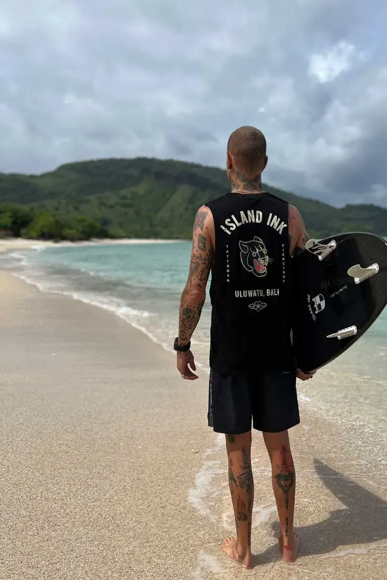 Clayton at the beach with a surfboard under his arm